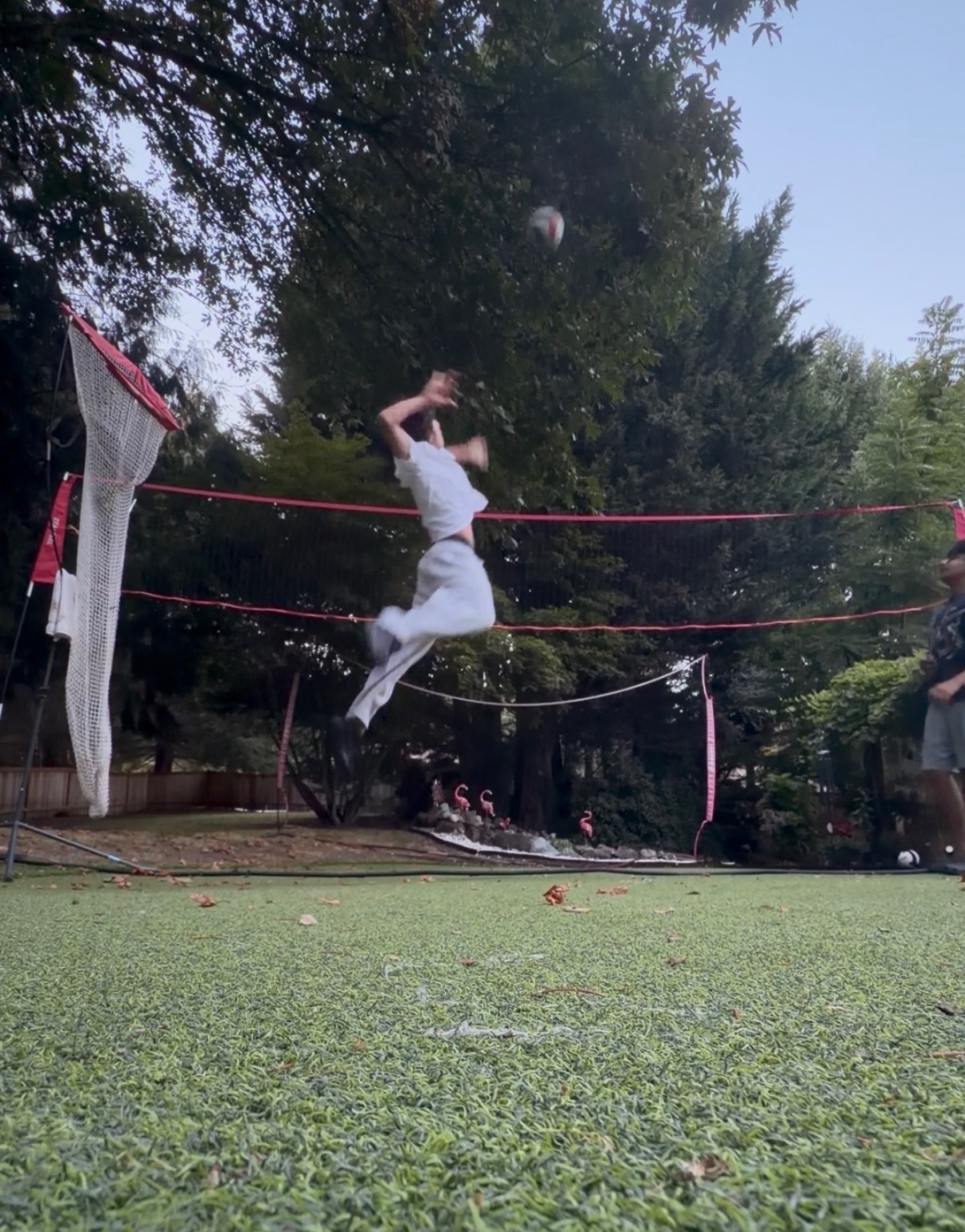 Aadi jumping to hit a volleyball over the net in his backyard.