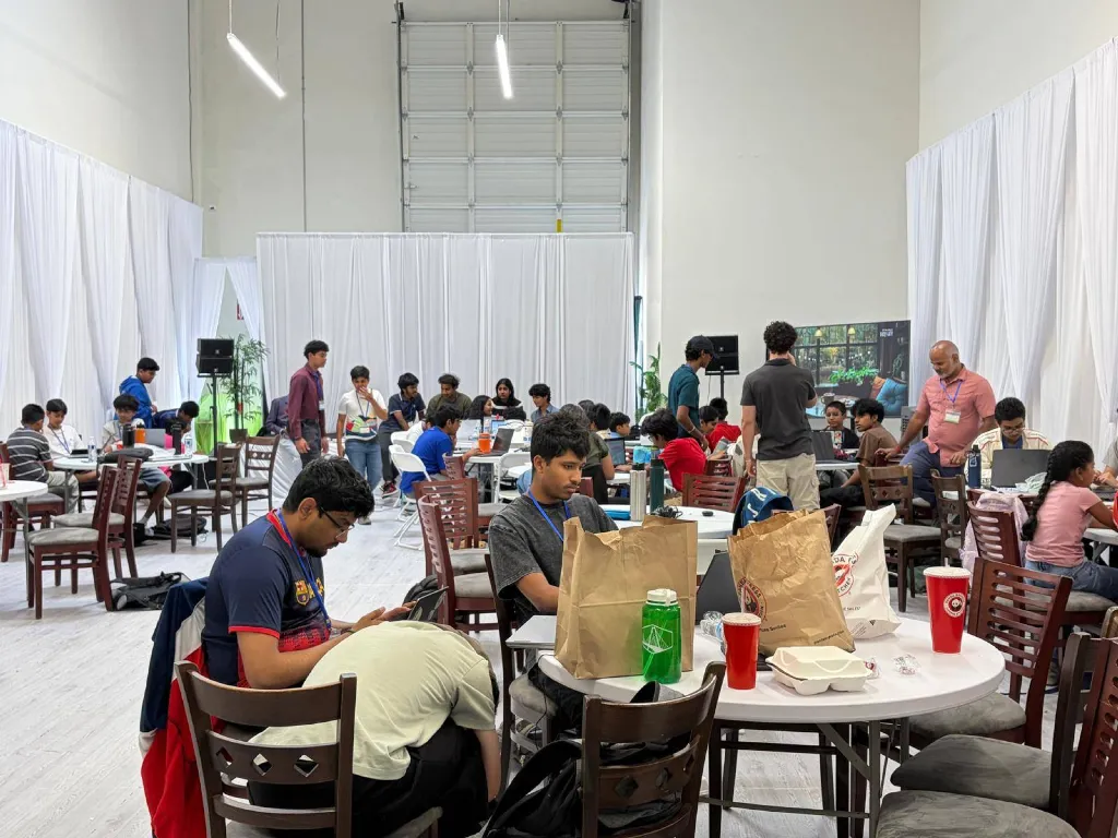 Students working together at tables during the AIXellerate hackathon.