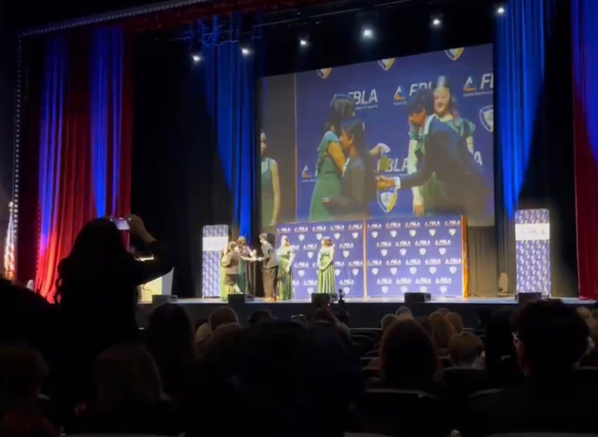 Aadi accepting the CammyCare award on stage at the FBLA state competition.